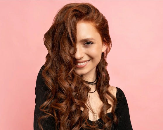 Fashion model showcasing luxury fashion tops with flowing hair against a pink background